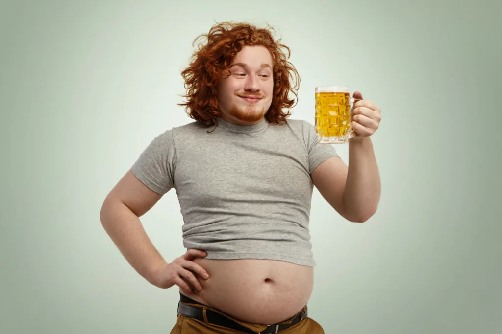 jovem com uma caneca de cerveja com uma grande barriga exposta.