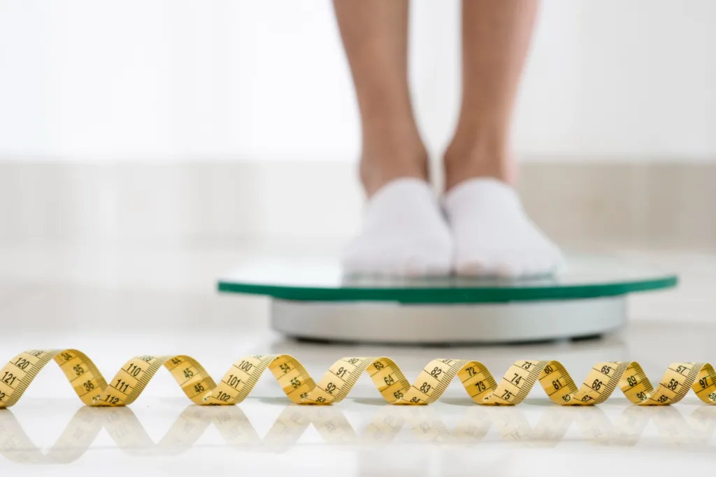 pessoa de meias brancas aferindo peso em uma balança domestica.