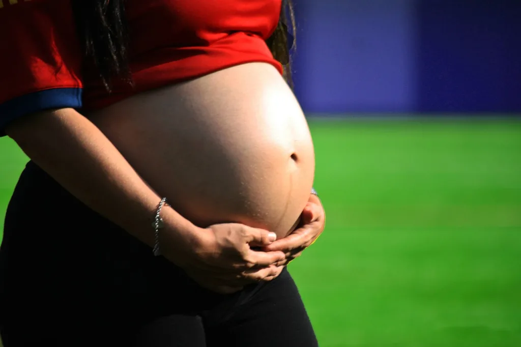 gravida apoiando sua barriga com as mãos.